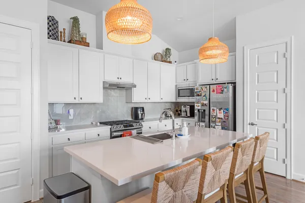 a kitchen with stainless steel appliances granite countertop a sink a stove a refrigerator a dining table and chairs with wooden floor