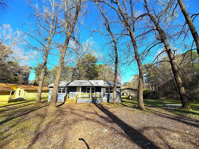 a view of a house with large trees and sitting area