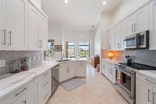 a large white kitchen with stainless steel appliances granite countertop lots of counter top space and a sink