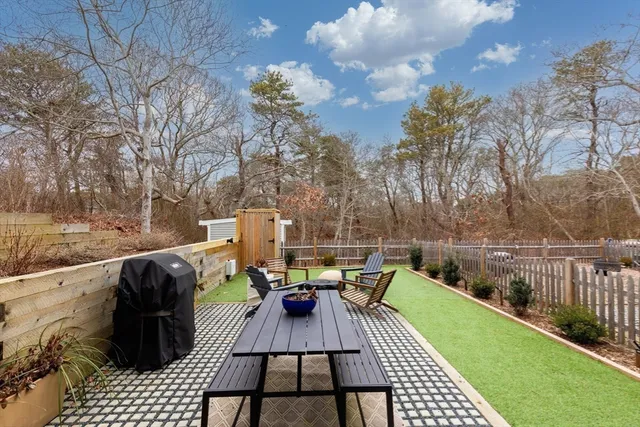 a view of a patio with couches and table and chairs with wooden fence and floor