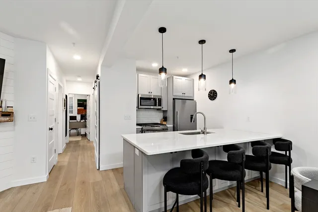 a kitchen with stainless steel appliances kitchen island granite countertop a table chairs and a refrigerator