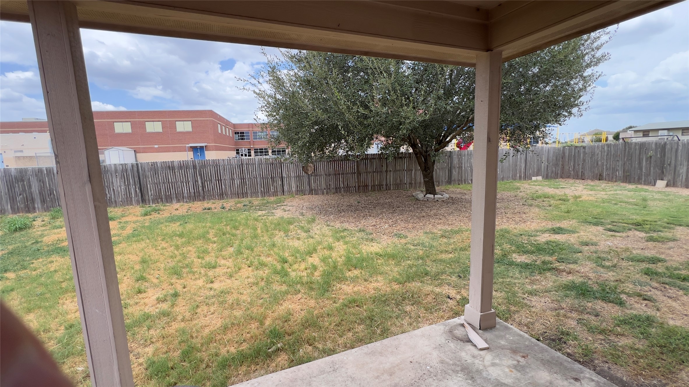 357 Nottingham Loop Kyle, TX 78640 - Photo 15 of 22 A covered back patio overlooks the fully fenced grassy yard featuring a mature shade tree.