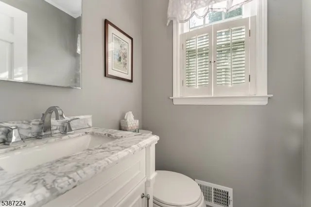 a bathroom with a granite countertop toilet sink and mirror