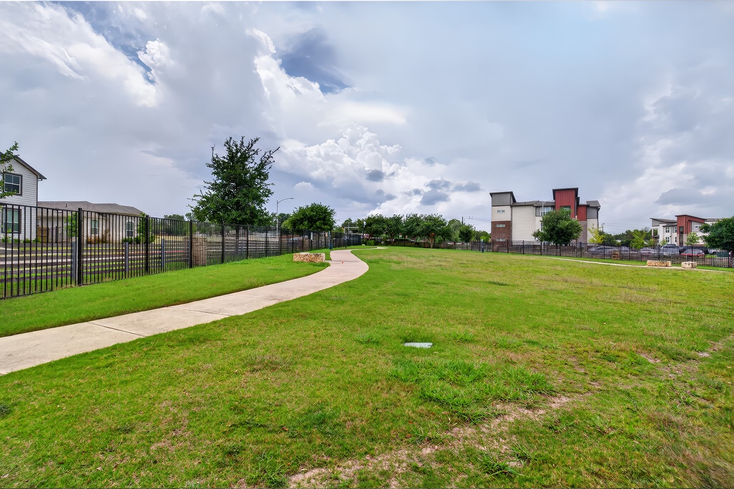 2006 Grow Lane Austin, TX 78754 - Photo 36 of 40 A winding pathway leads through a community green space, bordered by fencing and contemporary residences.