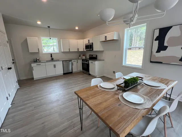 a kitchen with stainless steel appliances granite countertop a stove a kitchen island a table and chairs in it