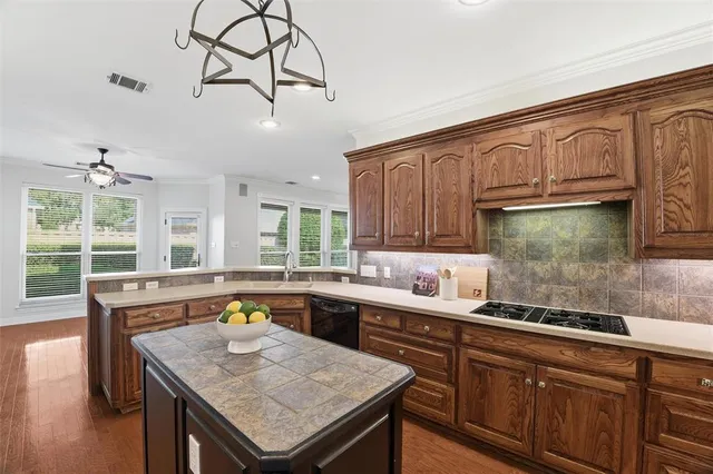 a kitchen with stainless steel appliances granite countertop a sink a stove and a wooden cabinets