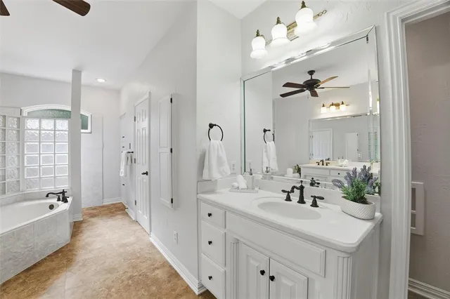a bathroom with a sink vanity tub shower and a mirror
