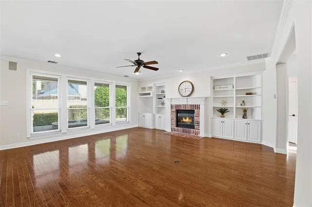 a view of an empty room with wooden floor fireplace and a window