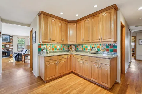 a kitchen with stainless steel appliances granite countertop a refrigerator a sink dishwasher and a stove with wooden floor