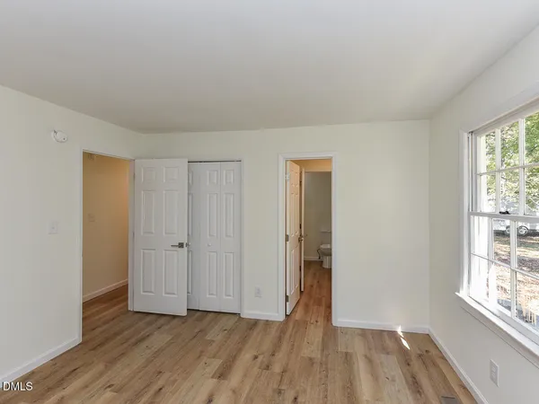 a view of an empty room with wooden floor and a window