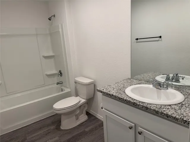 a bathroom with a granite countertop toilet a sink and a bathtub
