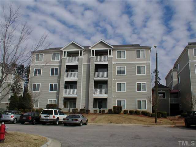a front view of a building with lot of cars and trees