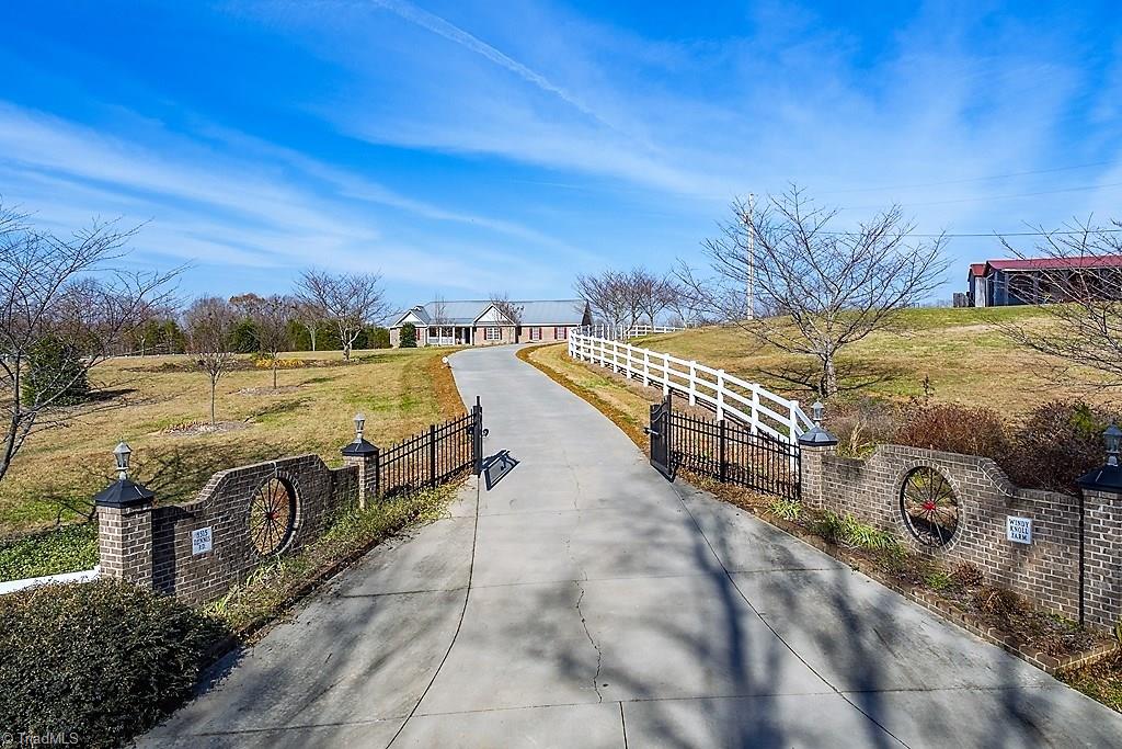 8315 Dennis Road Walnut Cove, NC 27052 - Photo 3 of 30 Gated Paved Drive Lined with Blooming Cherry Trees & Vinyl Fencing