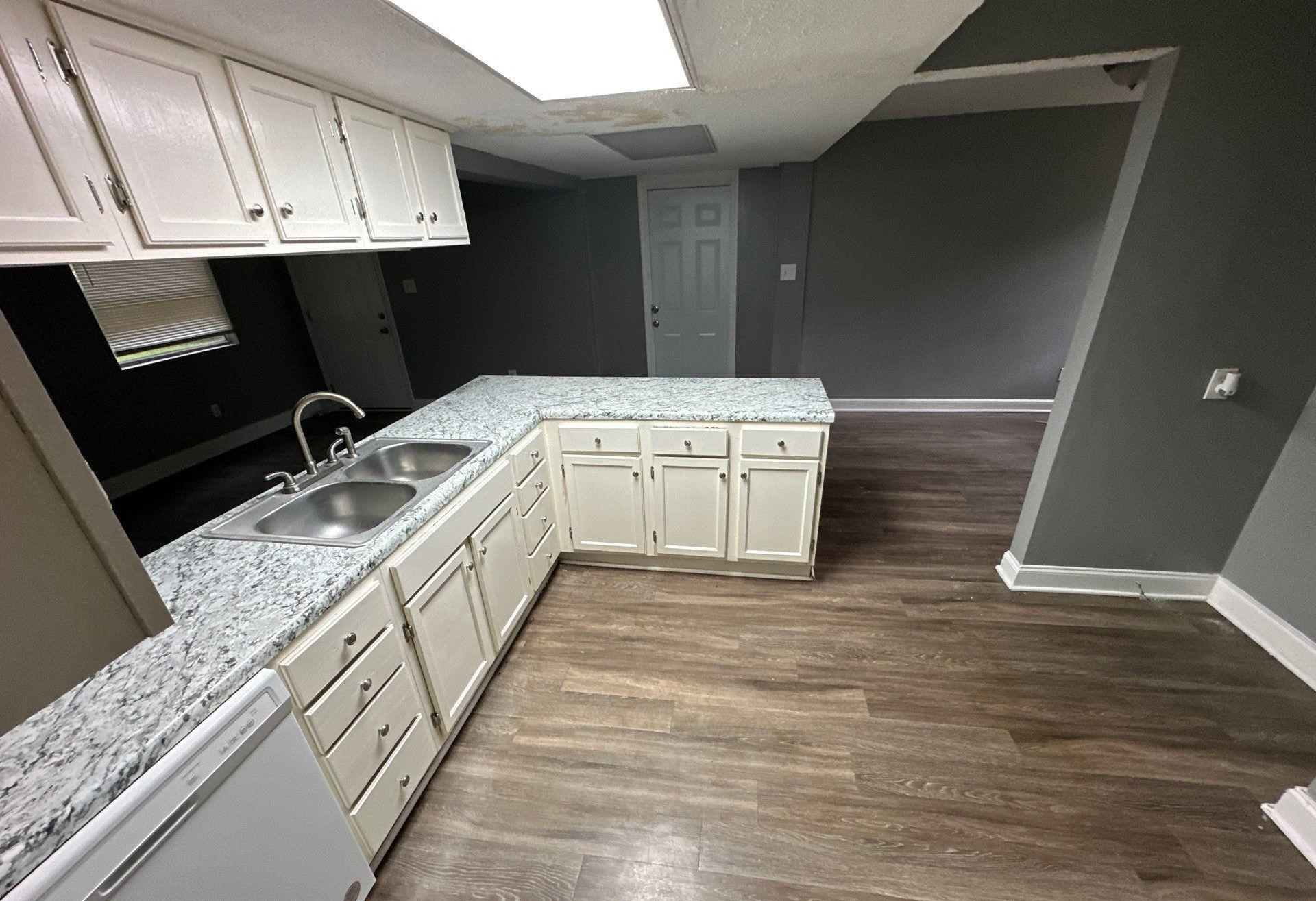 Kitchen featuring sink, wood-type flooring, kitchen peninsula, and white dishwasher