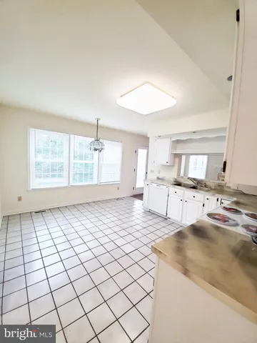 a large white kitchen with a stove a sink and a window