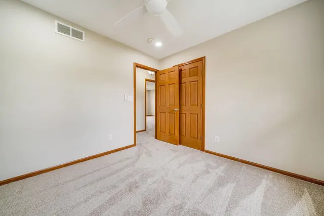 an empty room with windows and ceiling fan