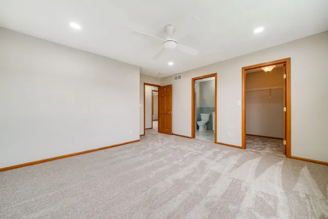 an empty room with a ceiling fan and carpet