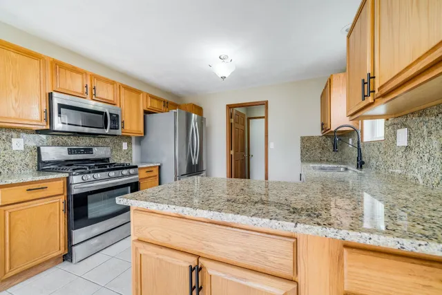 a kitchen with stainless steel appliances granite countertop a refrigerator and a stove top oven