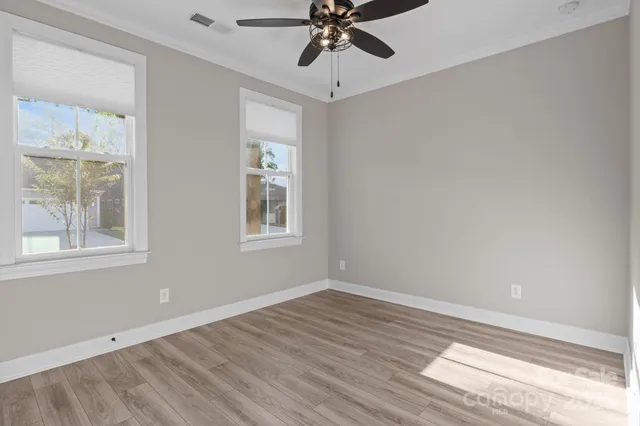 a view of an empty room with a window and wooden floor