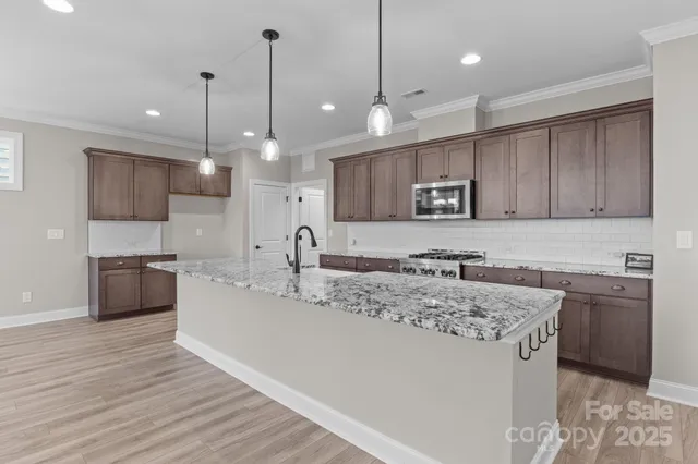 a kitchen with stainless steel appliances granite countertop a sink a stove and a wooden floors