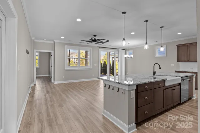 a kitchen with stainless steel appliances granite countertop a sink a stove and a wooden floors