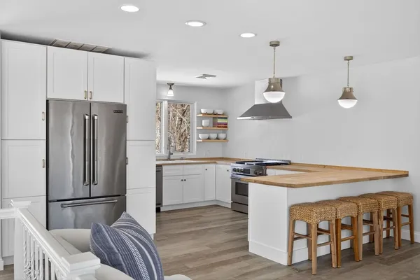 a kitchen with stainless steel appliances granite countertop a refrigerator a stove a sink and a dining table with wooden floor