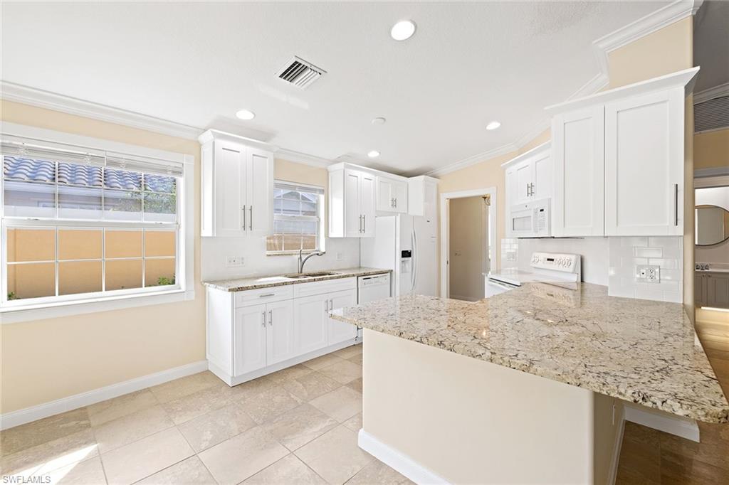 7539 Novara Court Naples, FL 34114 - Photo 9 of 30 a large kitchen with granite countertop a sink and white cabinets