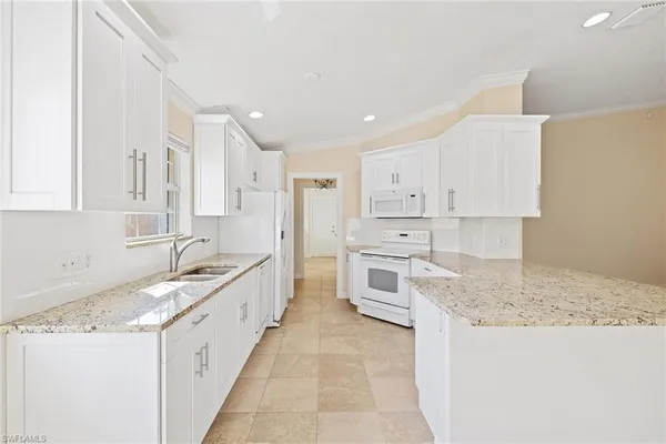 a large kitchen with granite countertop a sink and white cabinets