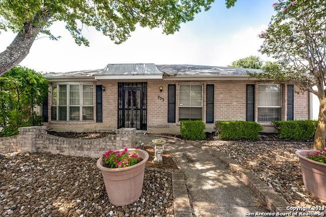 a view of a brick house with potted plants and a large tree