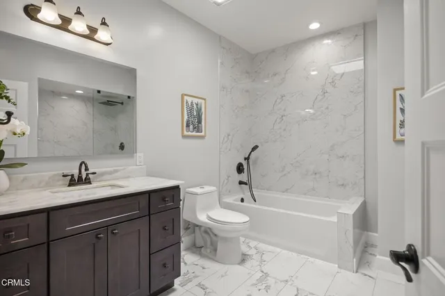 a bathroom with a bathtub shower sink vanity mirror and toilet
