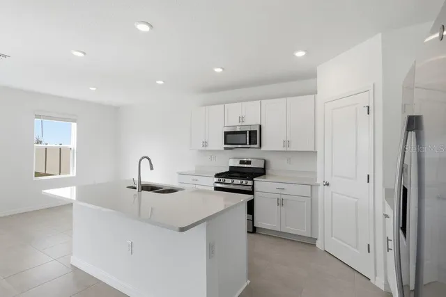 a kitchen with stainless steel appliances a sink a stove a refrigerator a center island and cabinets