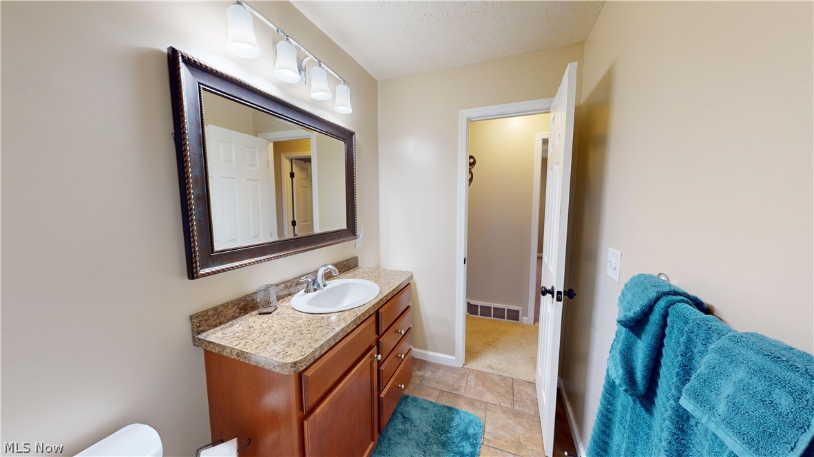 3805 Townline Road Madison, OH 44057 - Photo 16 of 38 Bathroom featuring vanity, tile patterned flooring, toilet, and a textured ceiling