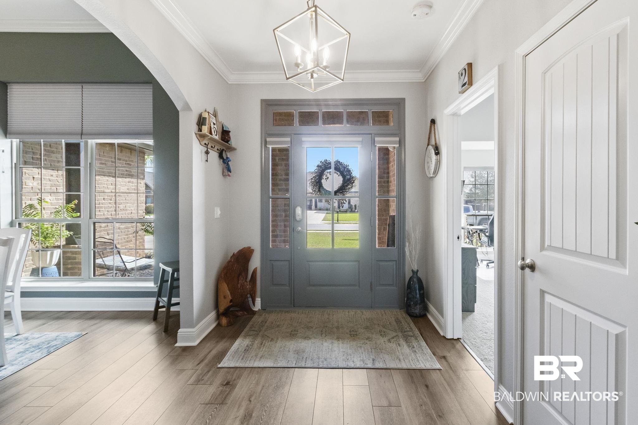 7051 Rocky Rd Loop Gulf Shores, AL 36542 - Photo 6 of 27 Entryway featuring wood finished floors, arched walkways, crown molding, baseboards, and a chandelier