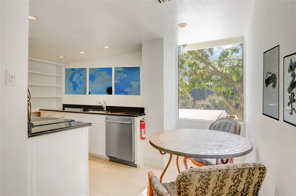 a kitchen with stainless steel appliances granite countertop a stove a refrigerator a sink a dining table and chairs