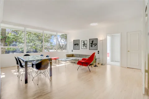a living room with furniture a rug potted plant and a large window