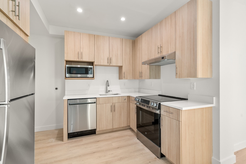 1151 Walnut Street, Unit 207 Newton, MA 02461 - Photo 24 of 27 a kitchen with stainless steel appliances granite countertop a stove a refrigerator and a sink