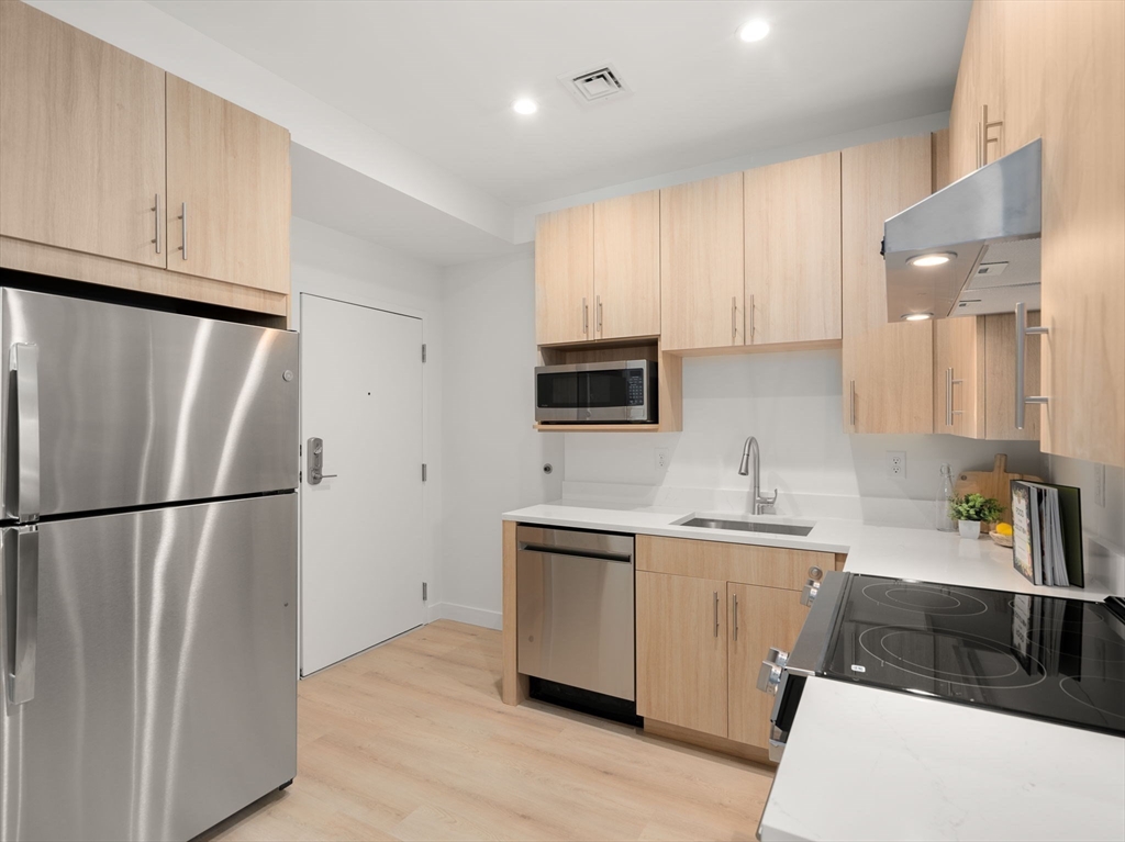 1151 Walnut Street, Unit 207 Newton, MA 02461 - Photo 8 of 27 a kitchen with stainless steel appliances a refrigerator sink and microwave
