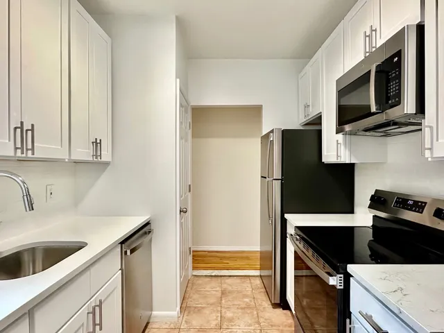 a kitchen with stainless steel appliances white cabinets and a window