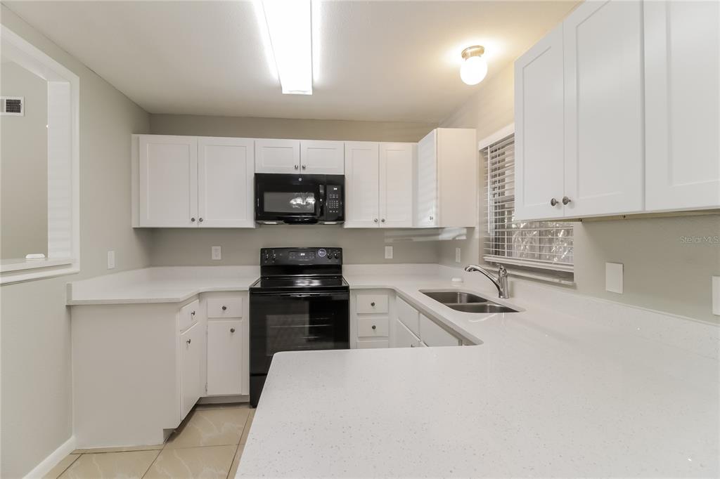 3014 Windchime Circle West Apopka, FL 32703 - Photo 4 of 16 a kitchen with granite countertop a sink and white cabinets