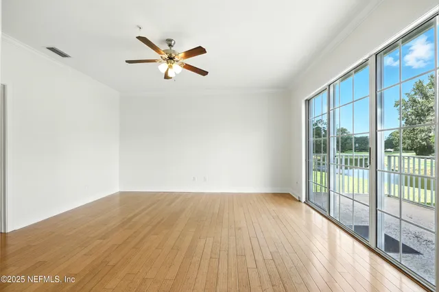 an empty room with window and ceiling fan