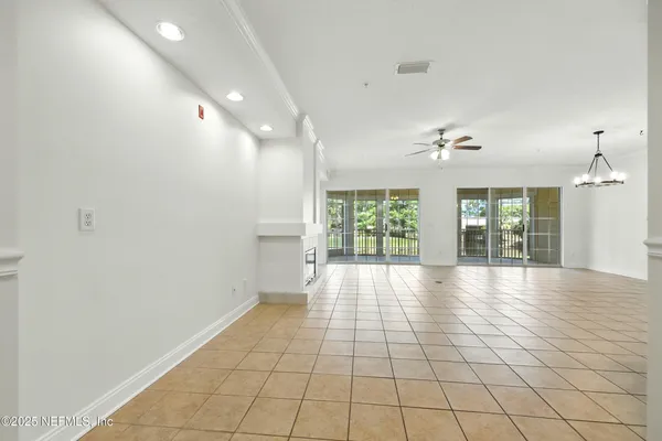 a view of an empty room and kitchen view of wooden floor