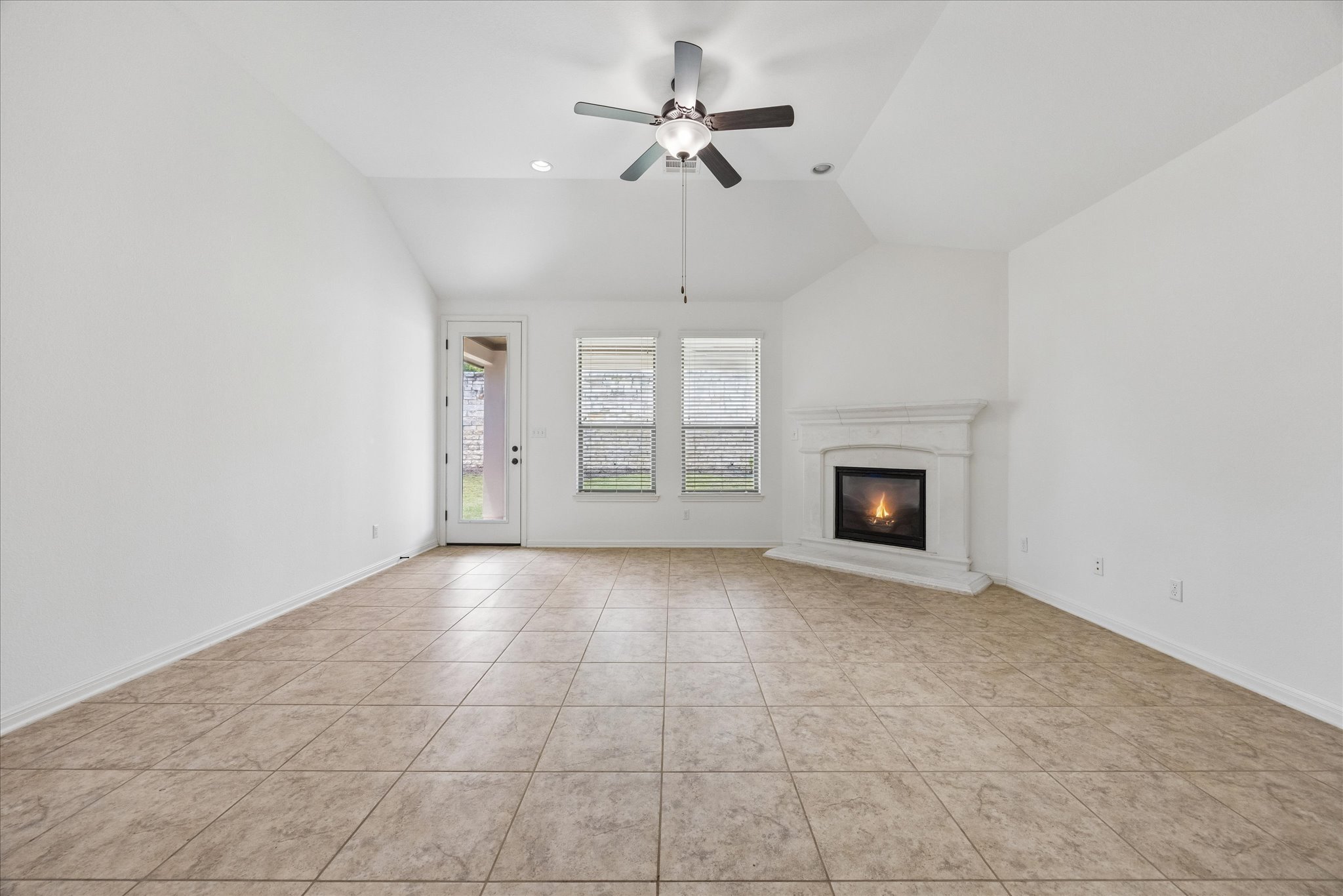 14304 Senia Bend Austin, TX 78738 - Photo 5 of 15 Invitingfamily room showcasing a cozy fireplace, vaulted ceilings, and direct access to outdoor living.