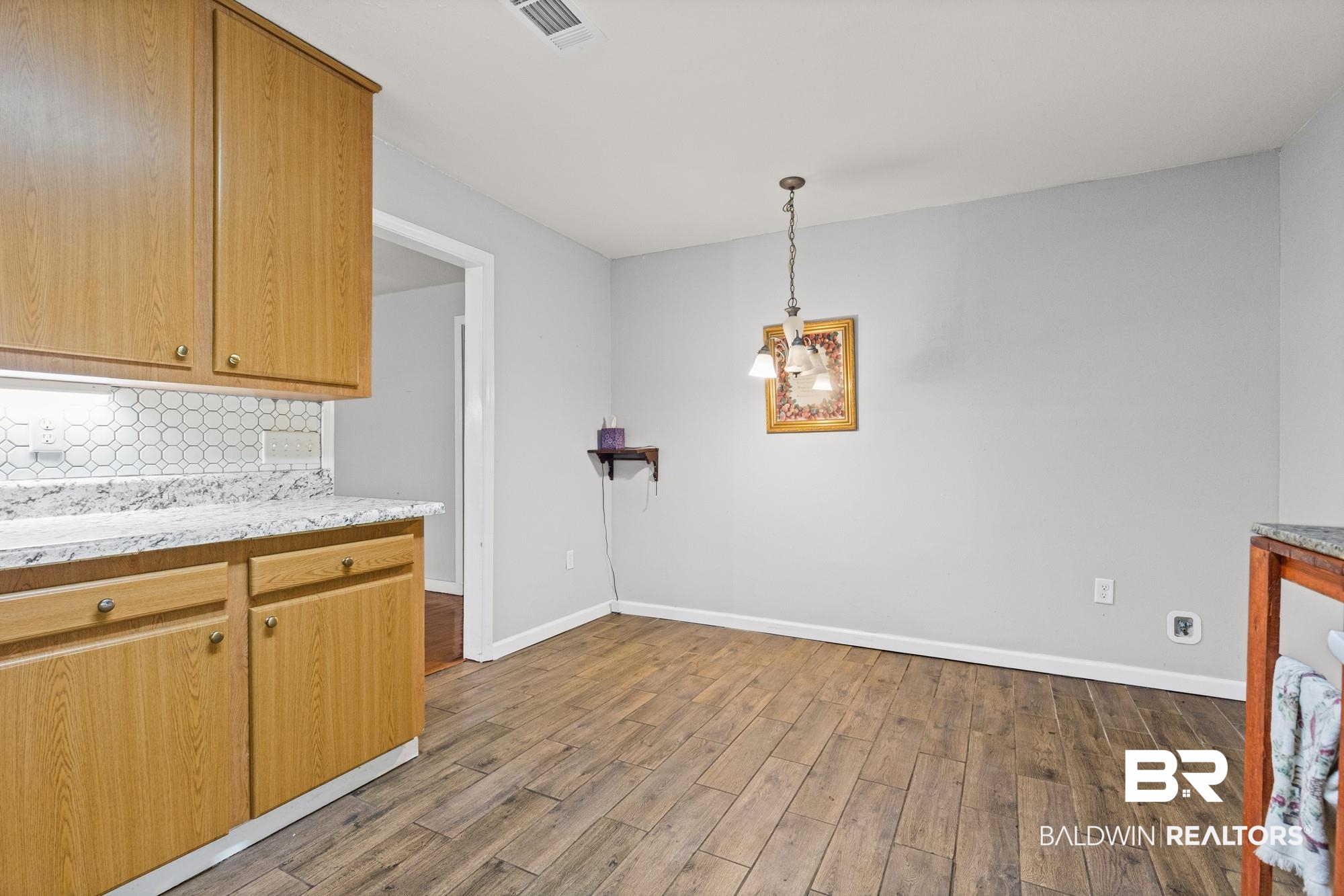 312 Sutherland Drive Mobile, AL 36611 - Photo 6 of 28 Kitchen area featuring wood-finish flooring, light wood cabinetry, a white penny tile backsplash, and light-toned countertops