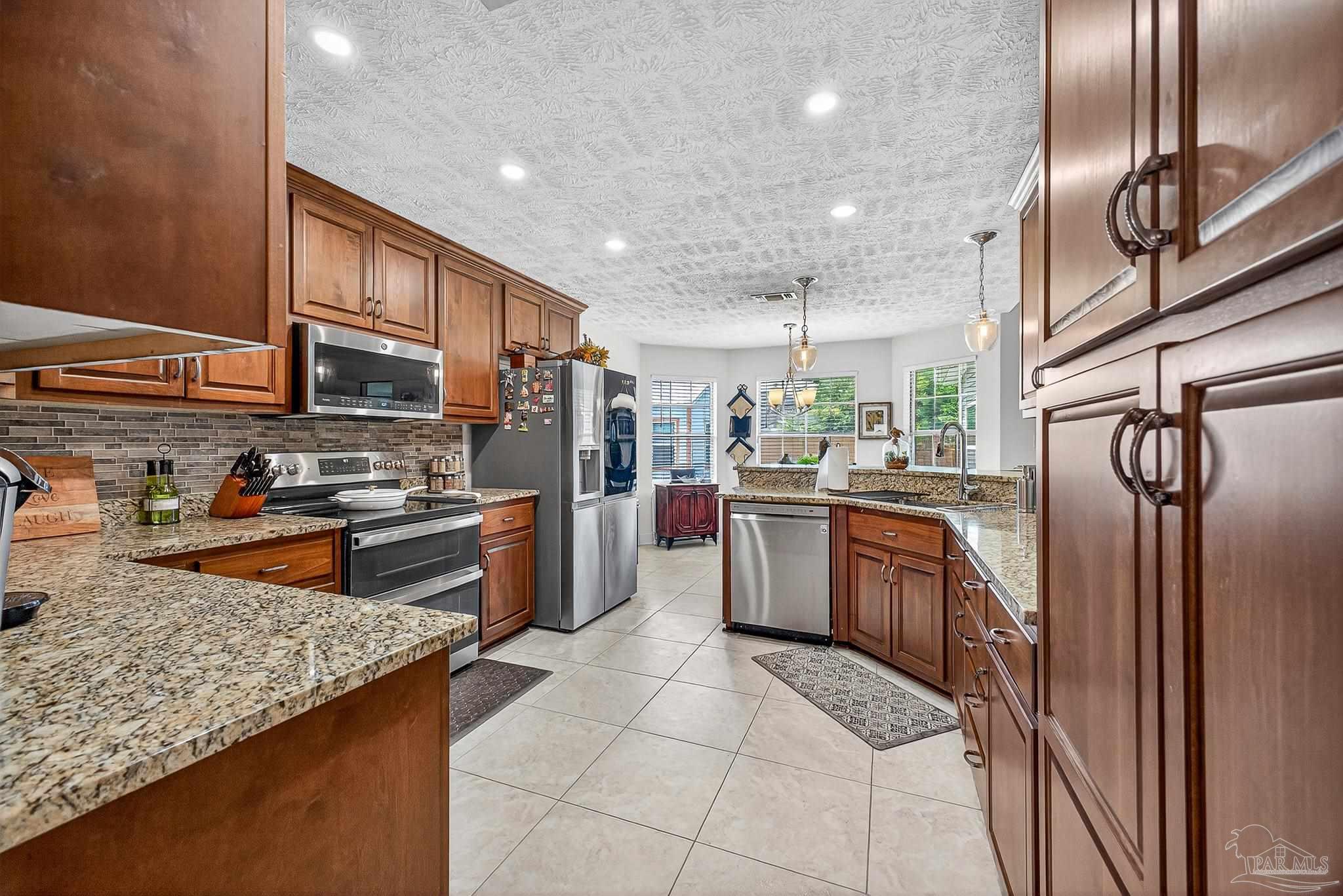 10051 Bristol Park Road Cantonment, FL 32533 - Photo 30 of 60 a kitchen with stainless steel appliances granite countertop a sink stove and refrigerator