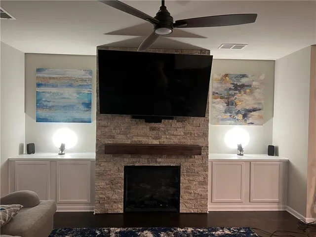 a living room with a fireplace and a ceiling fan