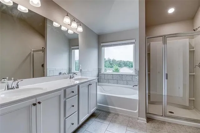 a spacious bathroom with a double vanity sink a large mirror and a bathtub