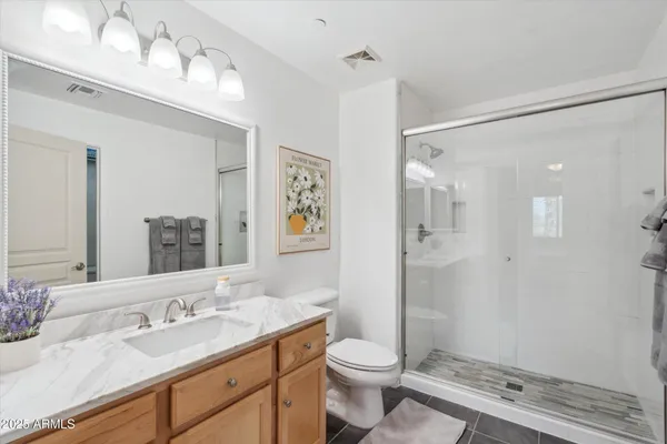 a bathroom with a granite countertop sink a toilet and shower