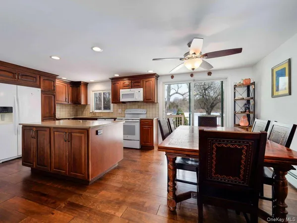 a open kitchen with stainless steel appliances granite countertop a stove a sink dishwasher a dining table and chairs with wooden floor