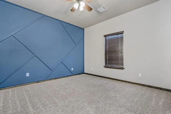 an empty room with a ceiling fan and window