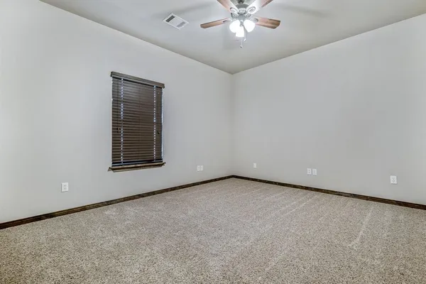 an empty room with a chandelier fan and windows